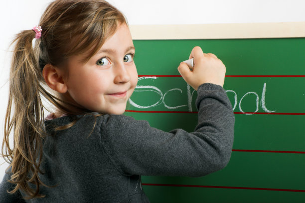 一个面带微笑的小女孩站在写着“学校”的板子上图片下载