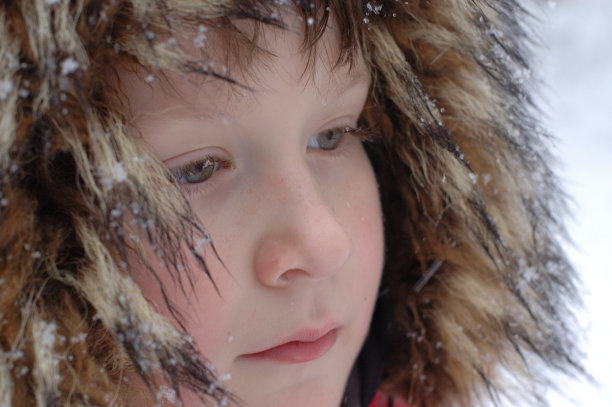 小男孩在冬天的皮帽上盖满了雪图片下载