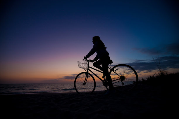 黄昏时骑自行车的沙滩女孩图片下载
