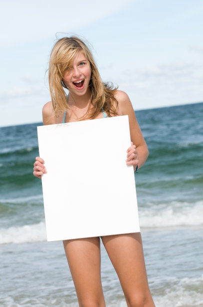 在海滩上有个写着空白标志的漂亮女孩图片下载