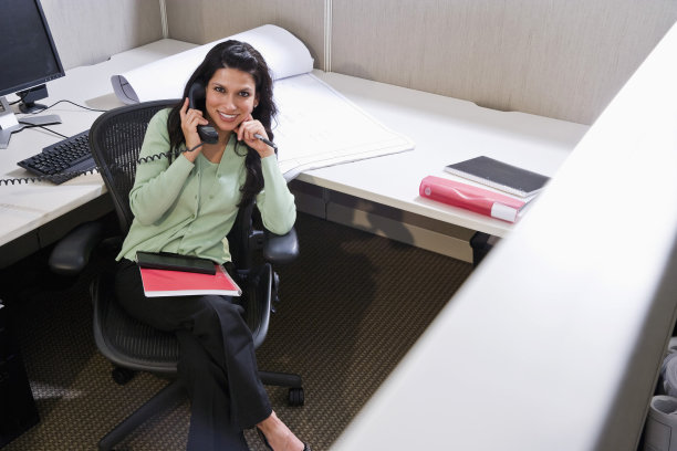拉丁裔女性在办公室小隔间里打电话图片下载