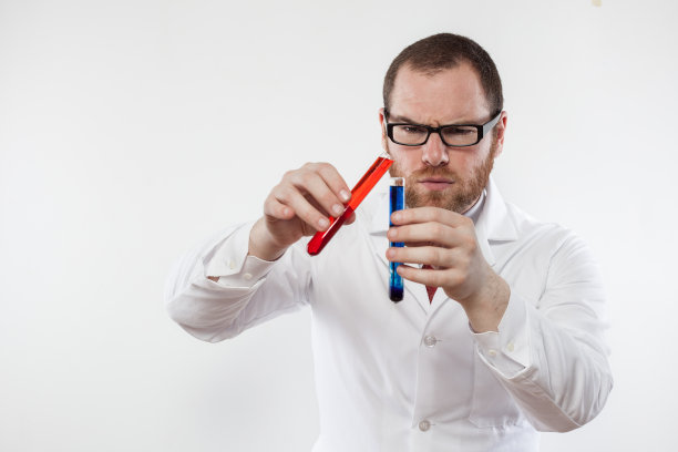 年轻的男性科学家正在混合两种有色化学物质图片下载