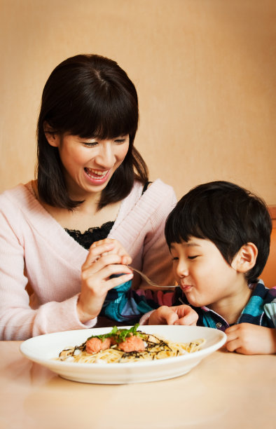 母亲和儿子在餐桌上愉快地吃着意大利面图片下载