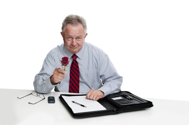 微笑着献上玫瑰的坐着的商人图片下载