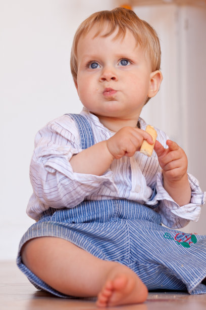 小男孩坐在地板上吃饼干图片下载