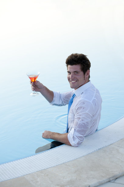 有吸引力的年轻人在游泳池里，喝一杯图片下载