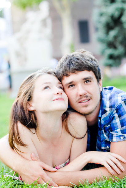 年轻幸福的一对男女躺在绿色的草坪上图片下载