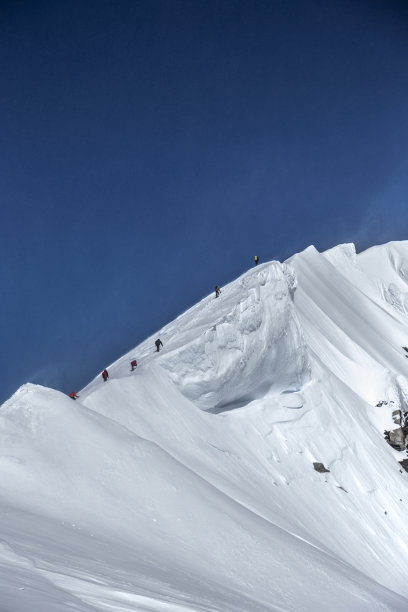 登山运动员在攀登积雪的山脊图片下载