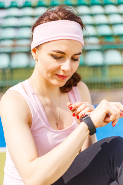 年轻微笑运动女性使用智能手表图片下载