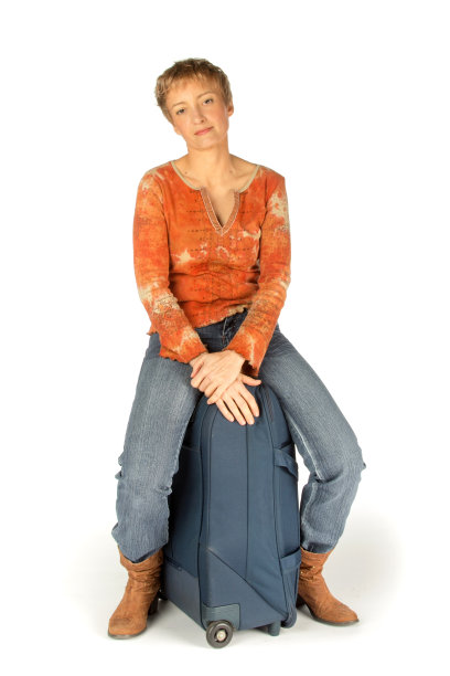 一个女人坐在她的手提箱上图片下载