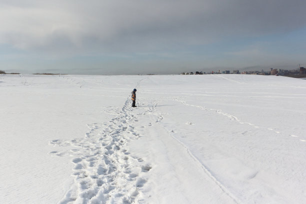 那个小男孩在下雪的河岸上行走图片下载