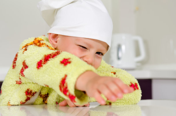 戴着厨师帽的男孩在柜台上伸展开来图片下载