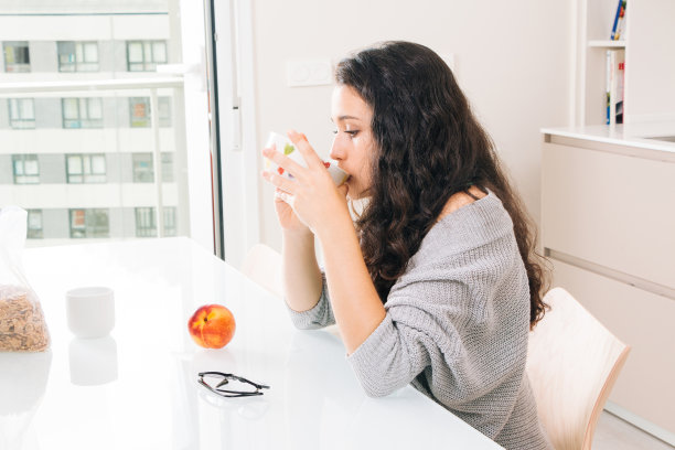 年轻女子在现代化的厨房里吃早餐图片下载