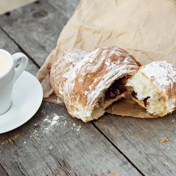 木桌上放着一杯浓咖啡和羊角面包。图片下载