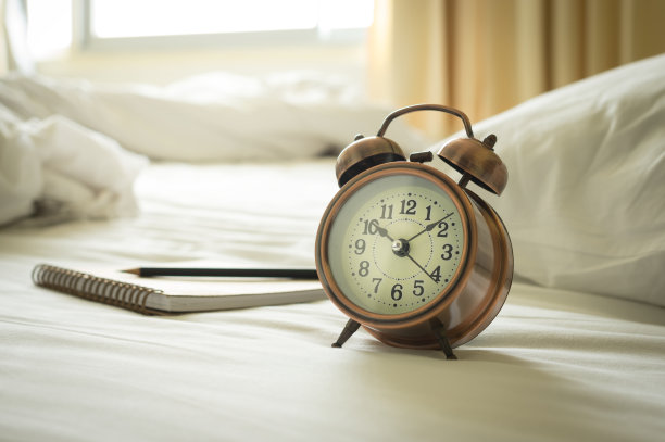 床上放着书和铅笔的时钟。图片下载