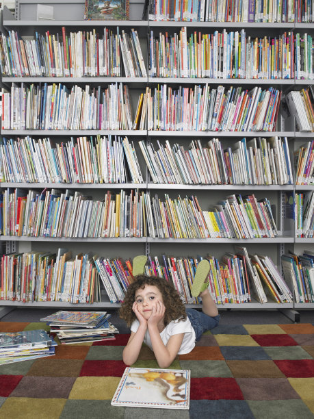 女孩躺在地板上的故事书在图书馆图片下载