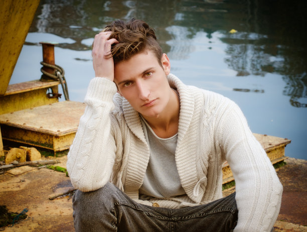 有魅力的年轻人坐在生锈的金属上图片下载