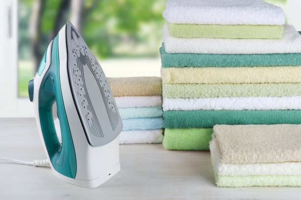 堆彩色毛巾和电熨斗，熨烫衣服的概念图片下载