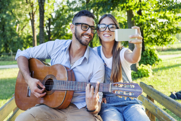 相爱的年轻情侣一边弹吉他一边自拍图片下载
