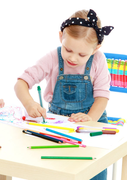 可爱的小女孩坐在桌前用马克笔画画。图片下载