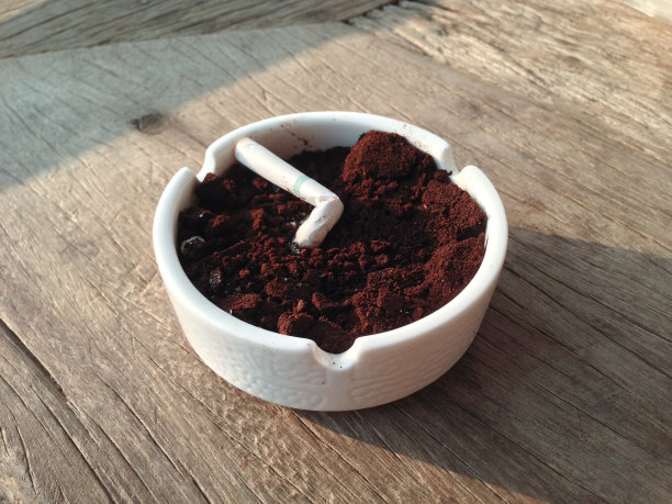 在桌子上的白色烟灰缸里抽烟图片下载