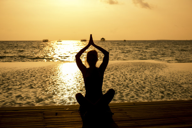 年轻女子坐在海滩上欣赏日落图片下载