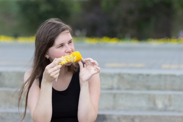 穿着黑t恤吃玉米的漂亮女孩图片下载