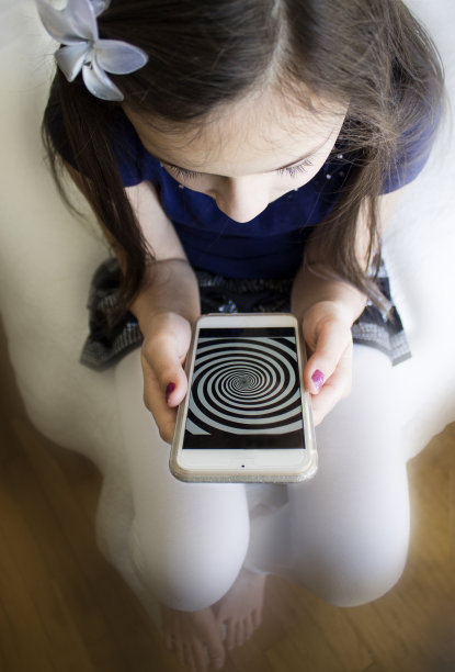 那女孩在看她手机上的催眠螺旋。图片下载