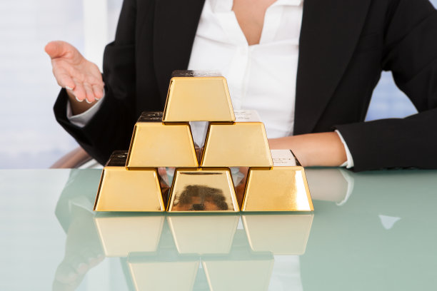 女商人在桌子上展示成堆的金块图片下载