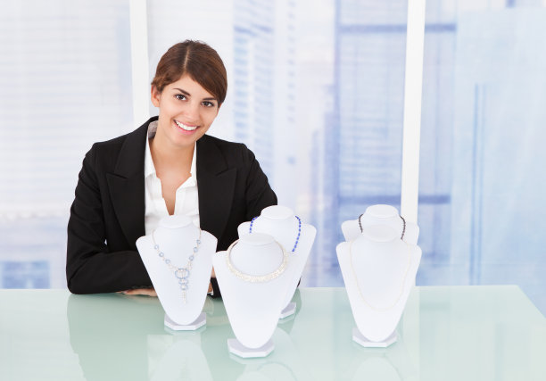自信的女售货员在桌子上展示珠宝图片下载