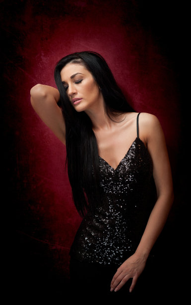 迷人的黑发女人在黑色摆出戏剧性的紫色背景图片下载
