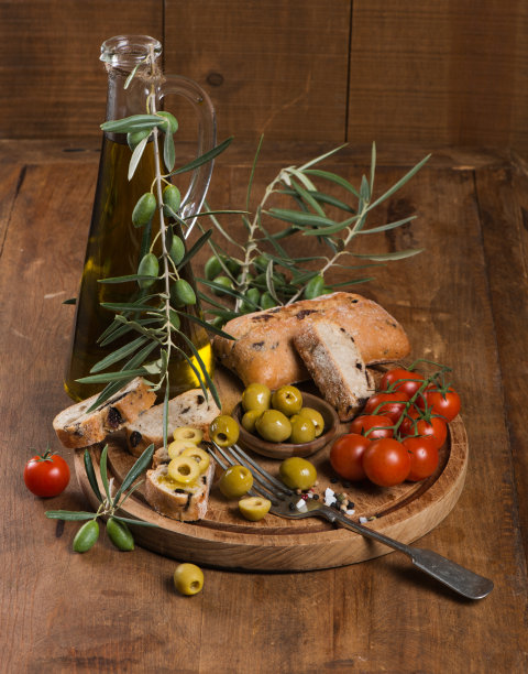 旧桌子上放着橄榄油和西红柿的橄榄面包图片下载
