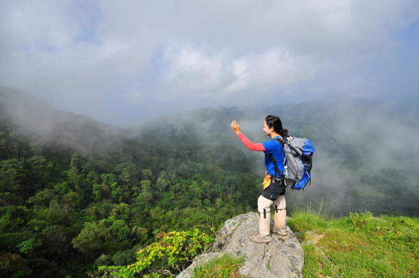 年轻女子背着背包站在悬崖边上图片下载