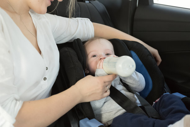 小男孩在汽车后座上喝瓶子里的牛奶图片下载