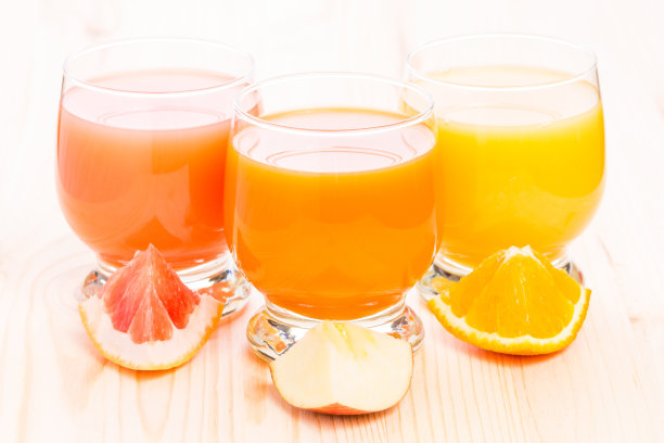 木桌上用玻璃杯盛着各种新鲜果汁。图片下载