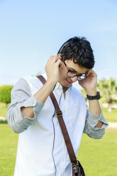 快乐的年轻人戴着耳机，面带微笑，在户外。图片下载