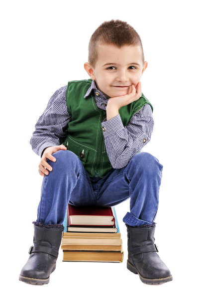 可爱的小男孩坐在一堆书上微笑图片下载
