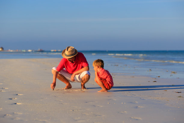 父亲和儿子在夏天的海滩上画画图片下载