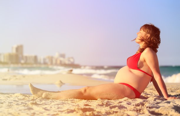 快乐的孕妇在海滩放松图片下载