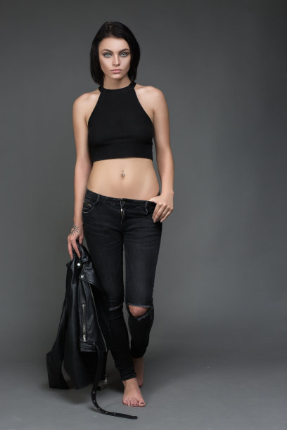 时尚模特穿着皮裤和夹克在灰色摆姿势图片下载