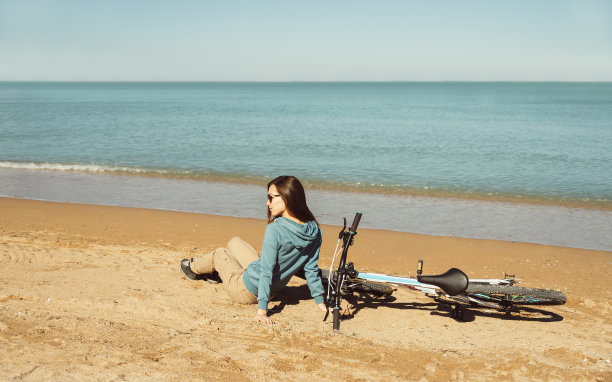 骑着自行车坐在海滩上的女人图片下载