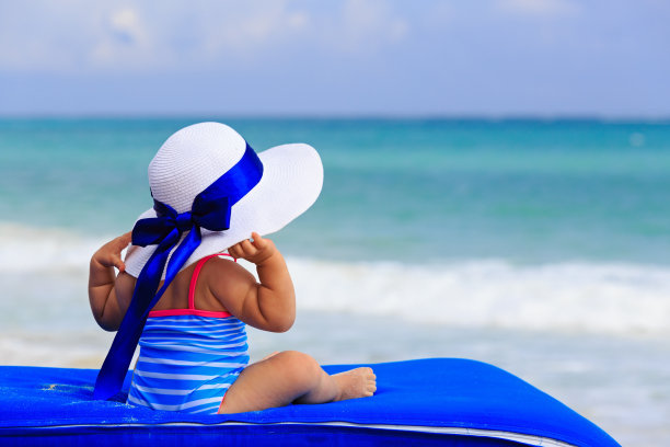 戴着大帽子的小女孩在夏天的海滩上图片下载