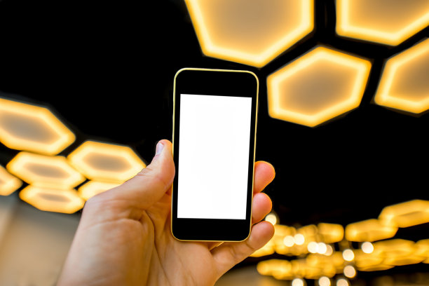 在现代灯光背景下拿着手机图片下载