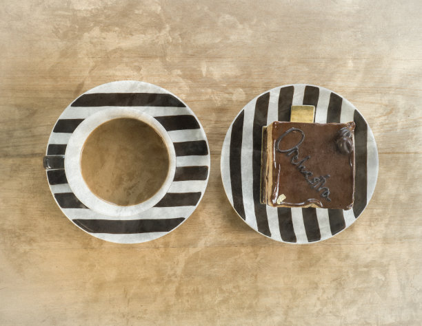 有条纹的盘子里有巧克力蛋糕和一杯咖啡。图片下载