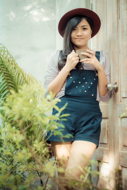 亚洲美丽的女孩在咖啡馆花园与咖啡微笑图片下载