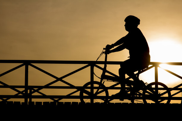 日落时一个骑自行车的人的剪影图片下载