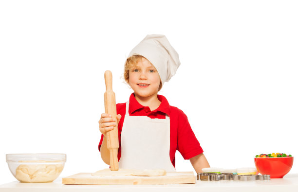 穿围裙戴帽的小男孩在烤饼干图片下载