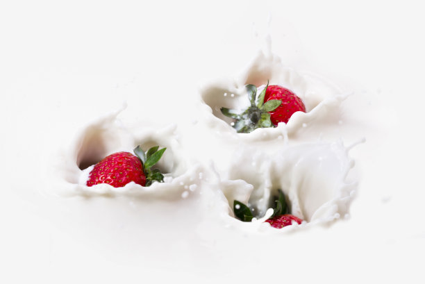 三颗草莓溅到牛奶里。图片下载