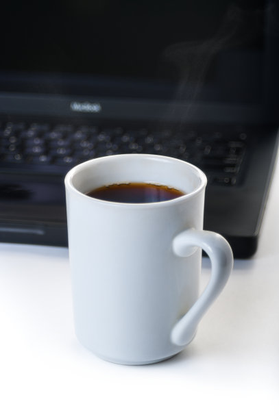 一杯热咖啡，背景是一台笔记本电脑图片下载