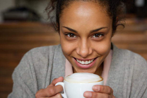 一位非洲裔美国妇女拿着一杯咖啡微笑着图片下载